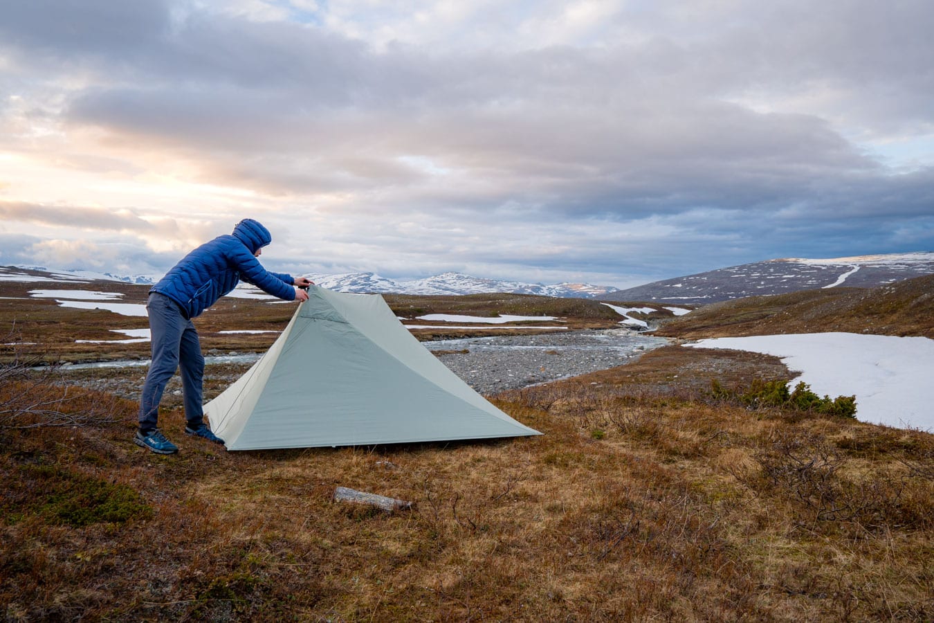 Hiker setting up a pyramid tent in Scandinavia